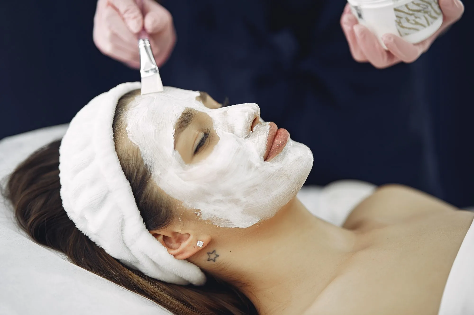 Client relaxing with a treatment mask during a facial