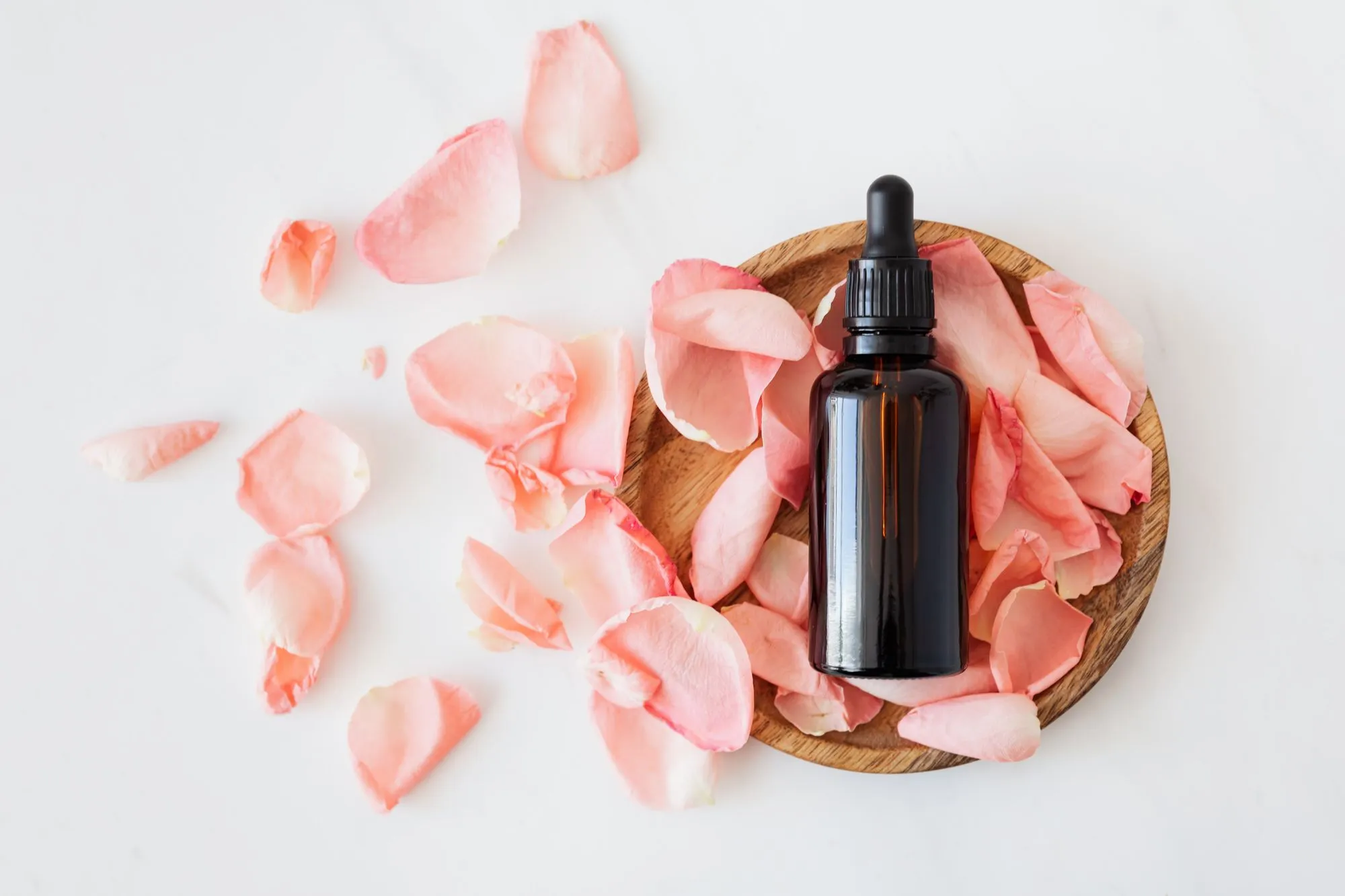 Skin care oil surrounded by rose petals